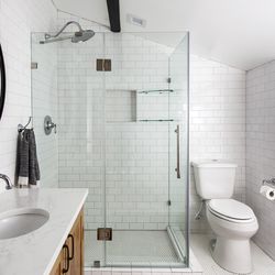 The shower showcases the oversize 5-by-7-inch subway tiles that line its walls, as well as the bath alcove’s; setting the tile in a herringbone pattern with gray grout amps up its visual interest. 