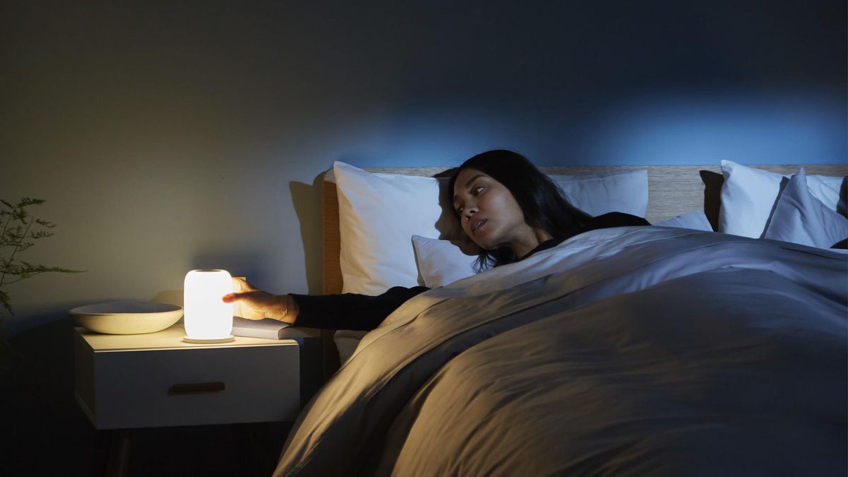 Woman laying in bed next to lamp