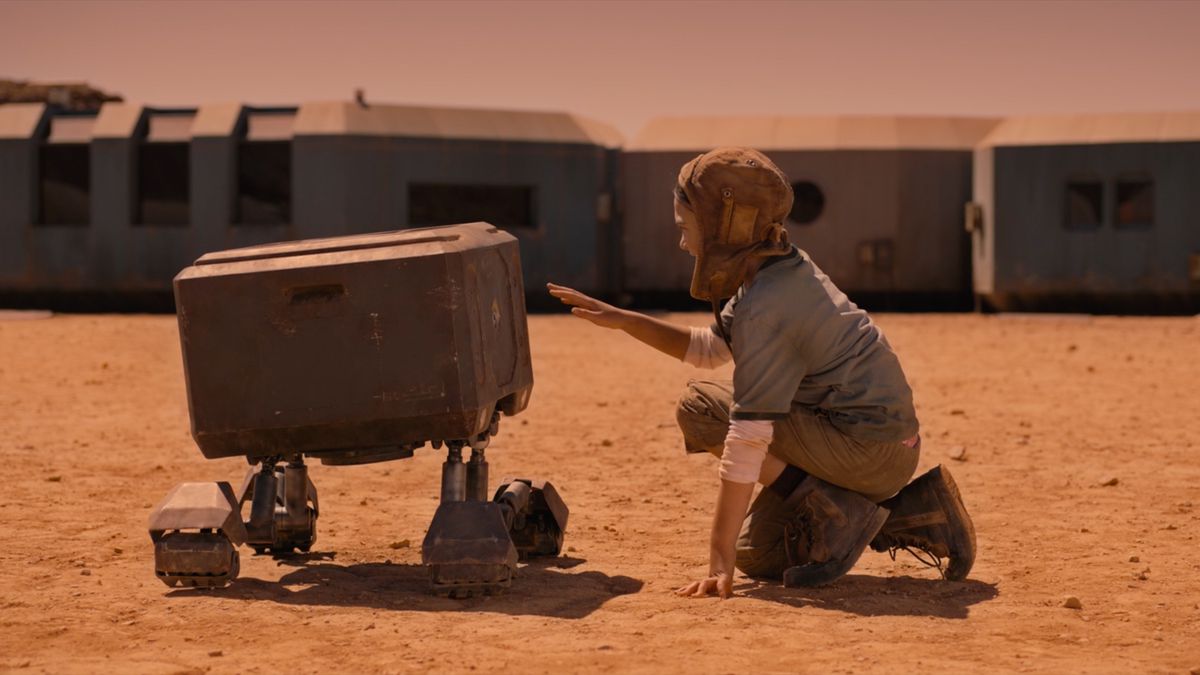 Brooklynn Prince as Remmy kneels to touch a boxy four-legged robot in Settlers