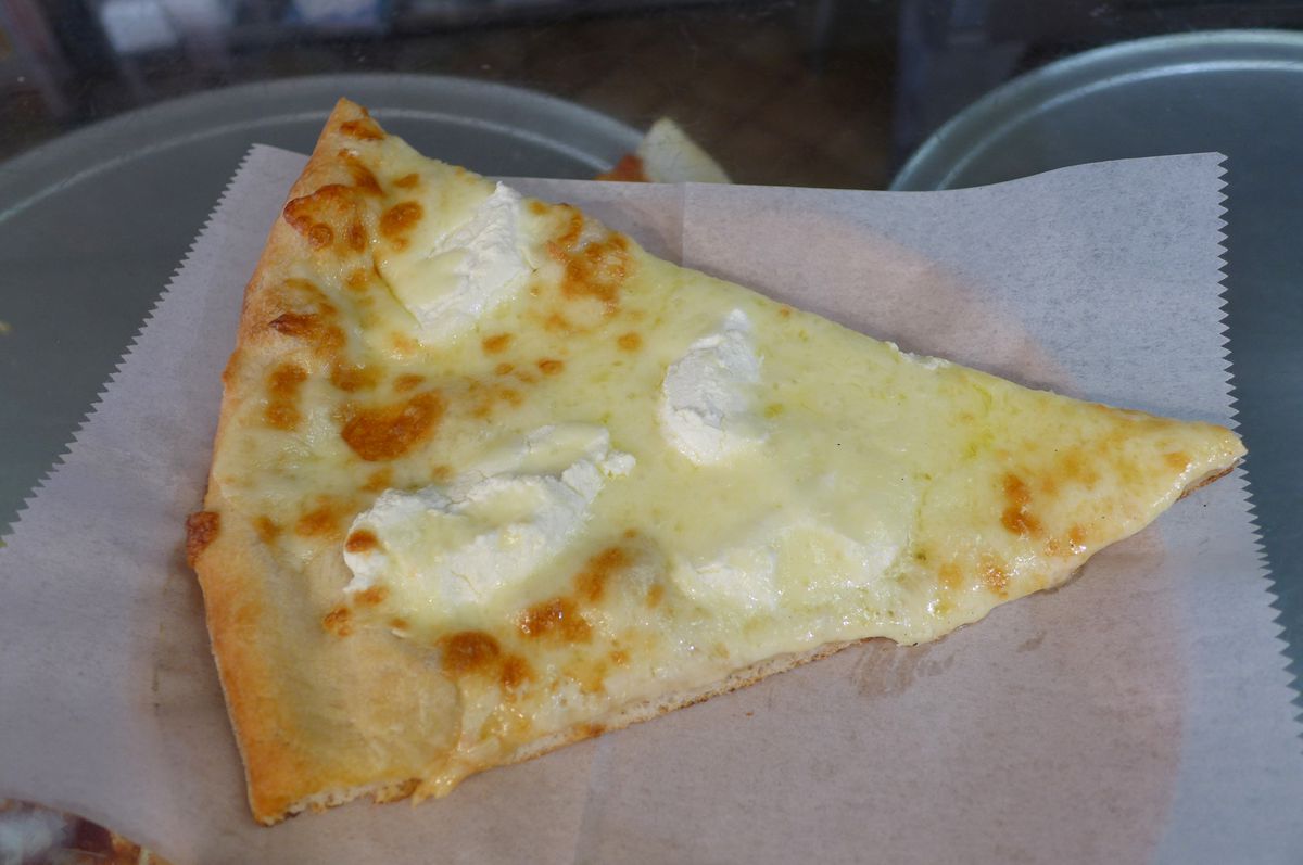 A wedge of white pizza with clumps of whiter ricotta.