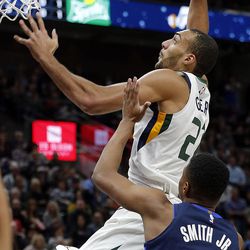 Utah Jazz center Rudy Gobert goes in for a dunk with Dallas Mavericks guard Dennis Smith Jr. defending during NBA basketball in Salt Lake City on Saturday, Feb. 24, 2018.