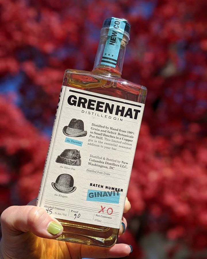 A bottle of Green Hat gin on a fuschia background