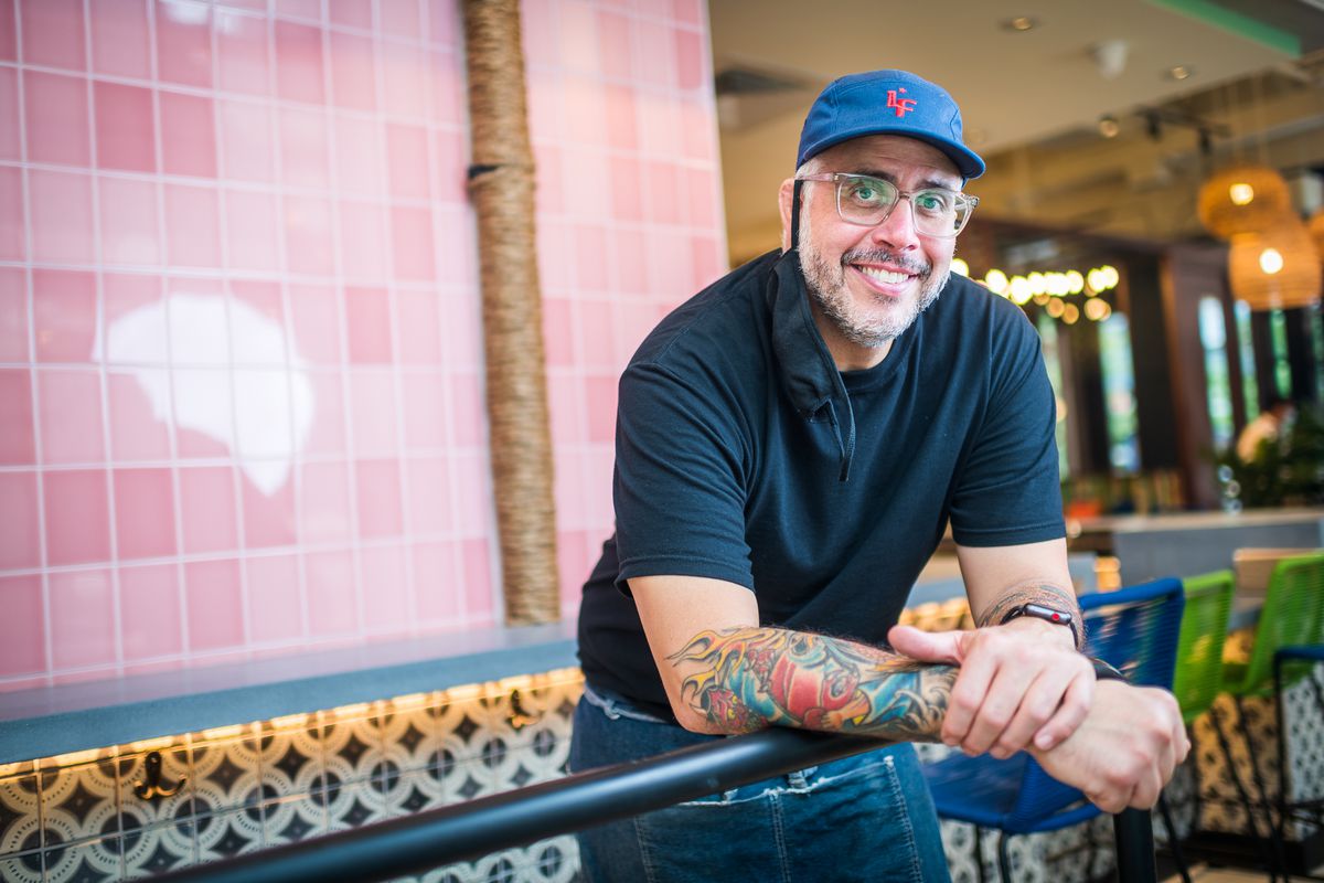 La Famosa chef Joancarlo Parkhurst poses for a portrait in glasses with see-through rims, a salt-and-pepper beard, and a blue ballcap with an “LF” logo