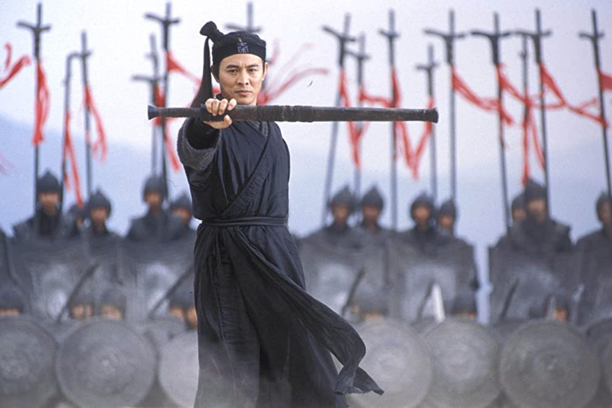 Jet Li stands with a sword in front of a group of warriors carrying standards and shields.