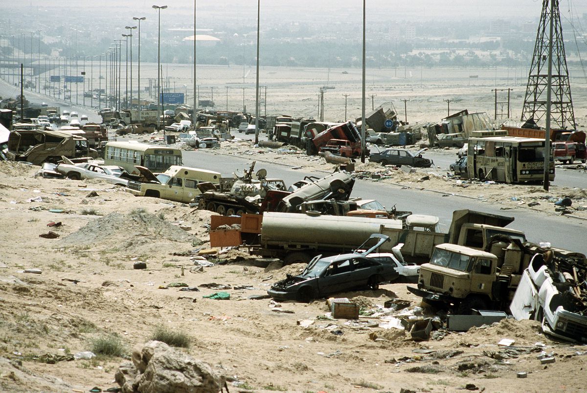 Ruined, burned-out cars, buses, and Iraqi tanks have been pushed to the side of Route 80 leading out of Kuwait during the first Gulf War.