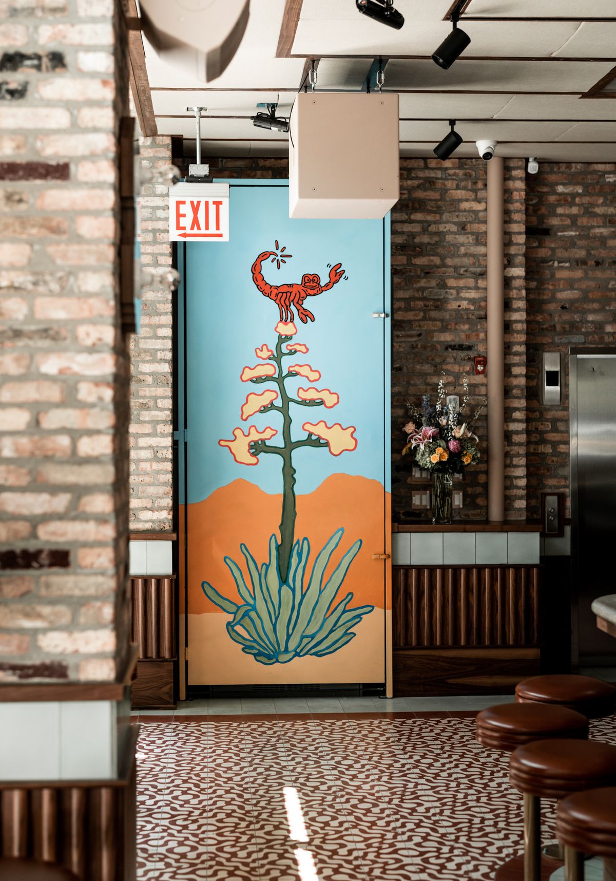 A door painted with a mural of an agave plant with a scorpion on top.