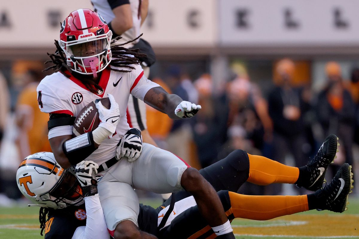 James Cook of the Georgia Bulldogs runs with the ball while being tackled by Roman Harrison of the Tennessee Volunteers in the first quarter at Neyland Stadium on November 13, 2021 in Knoxville, Tennessee.