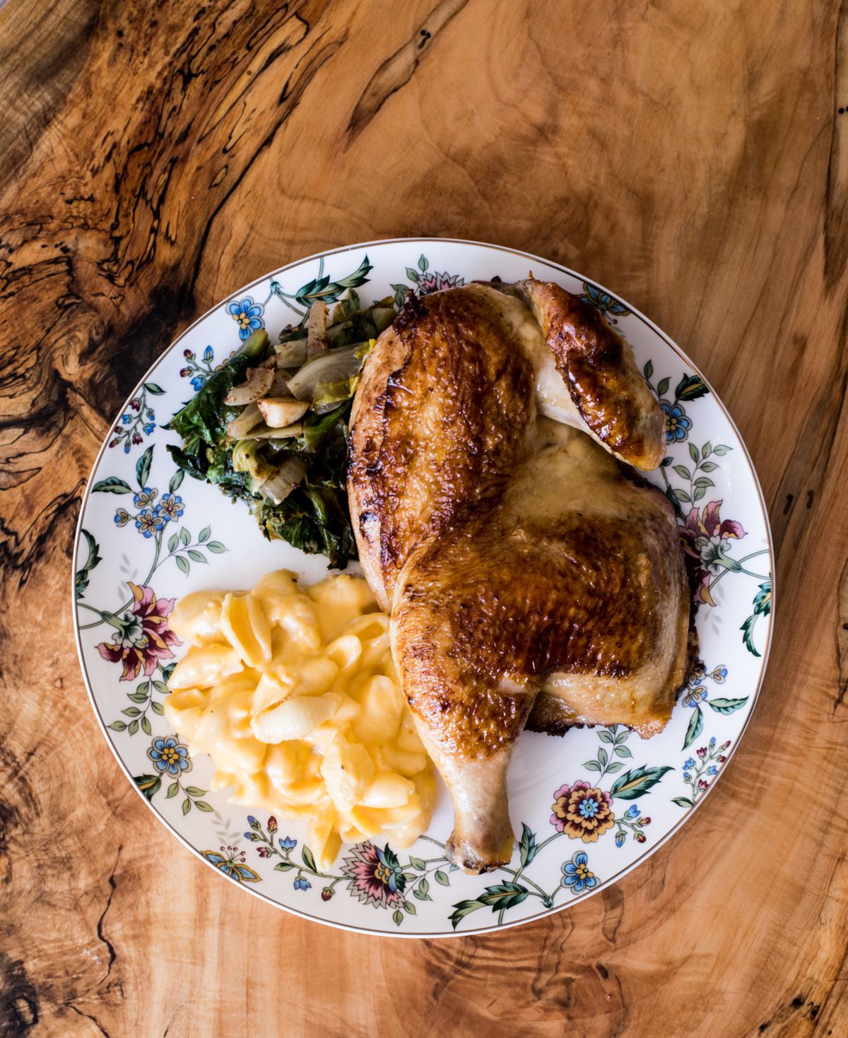 Roasted chicken with Brussels sprouts and mac and cheese on a floral plate.