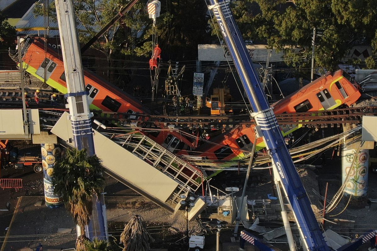 An aerial view of subway cars dangle at an angle from a collapsed elevated section of the metro, in Mexico City, Tuesday, May 4, 2021. The elevated section collapsed late Monday killing at least 23 people and injuring at least 79, city officials said. (AP Photo/Fernando Llano)