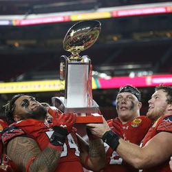 Utah Utes offensive lineman Isaac Asiata (54) and Utah Utes defensive end Hunter Dimick (49) lift the trophy after the Utes defeat the Indiana Hoosiers in the Foster Farms Bowl in Santa Clara, California, on Wednesday, Dec. 28, 2016.