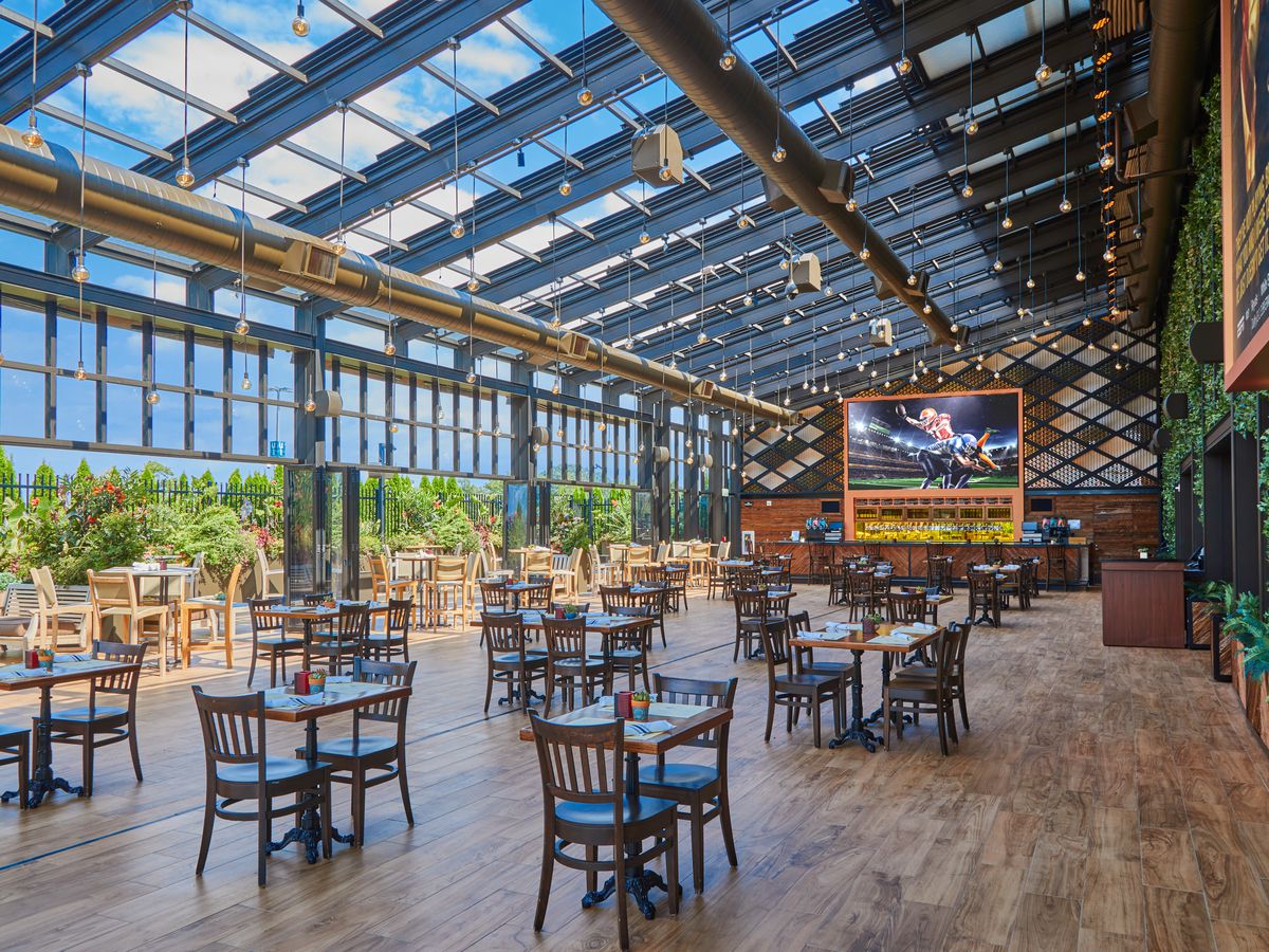 restaurant with glass roof, green wall, and projector screen next to patio 