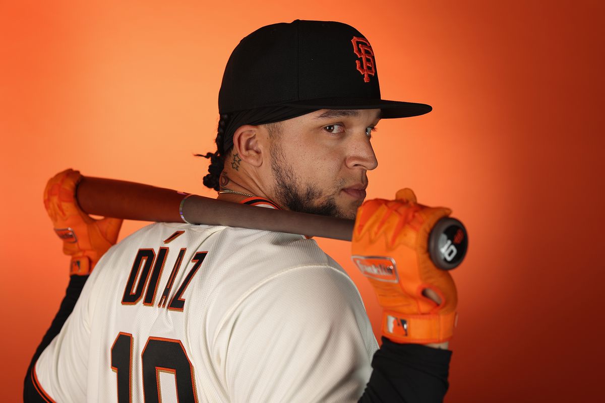 Isan Díaz posing at media day, holding a bat over his shoulders and looking back at the camera