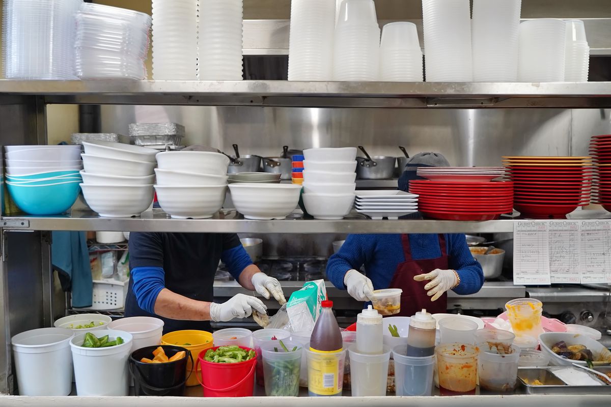 Two cooks wearing gloves in the kitchen