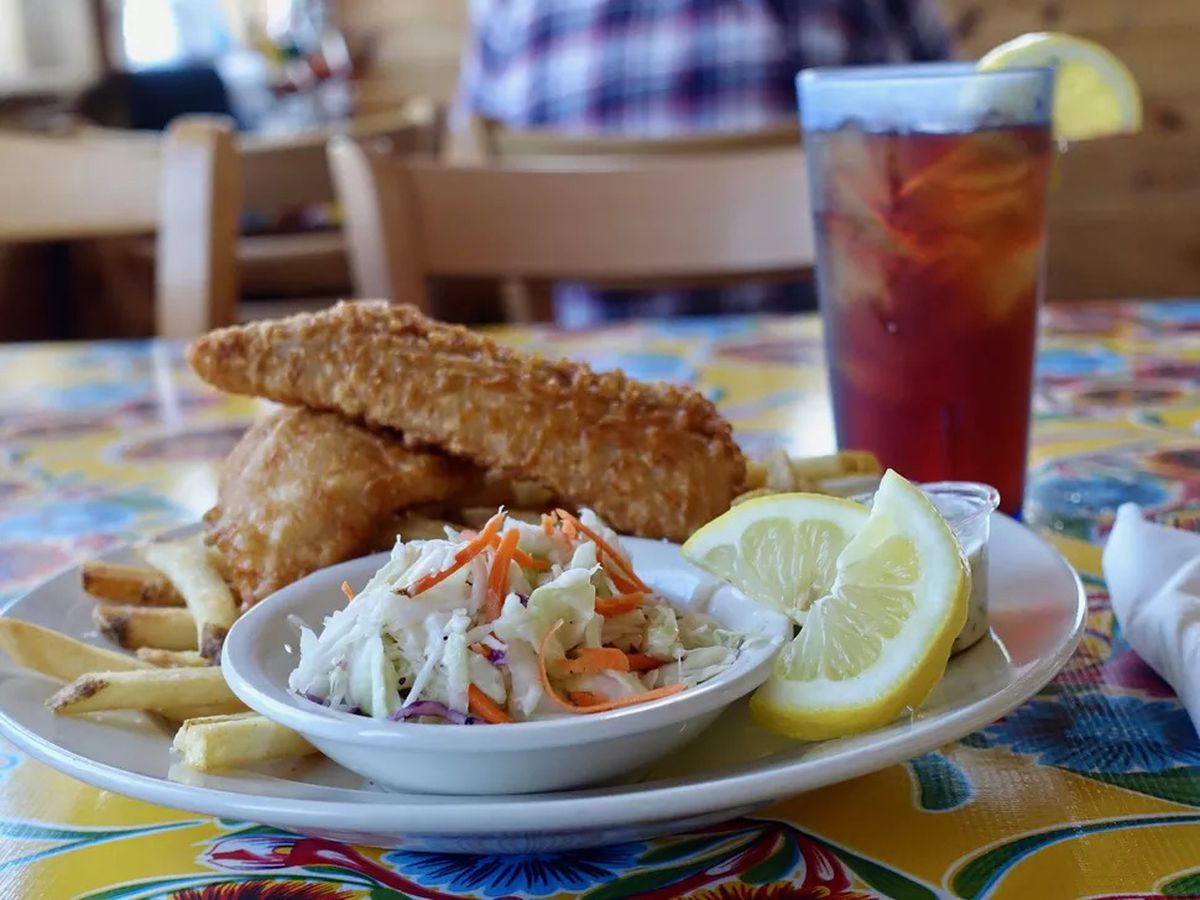 A picture of two breaded chunks of fish with medium-cut fries, a tiny bowl of slaw, and two lemon slices at Crazy Norwegian’s.