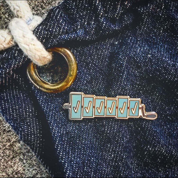 A closeup shot of a pin featuring check marks on a denim apron.