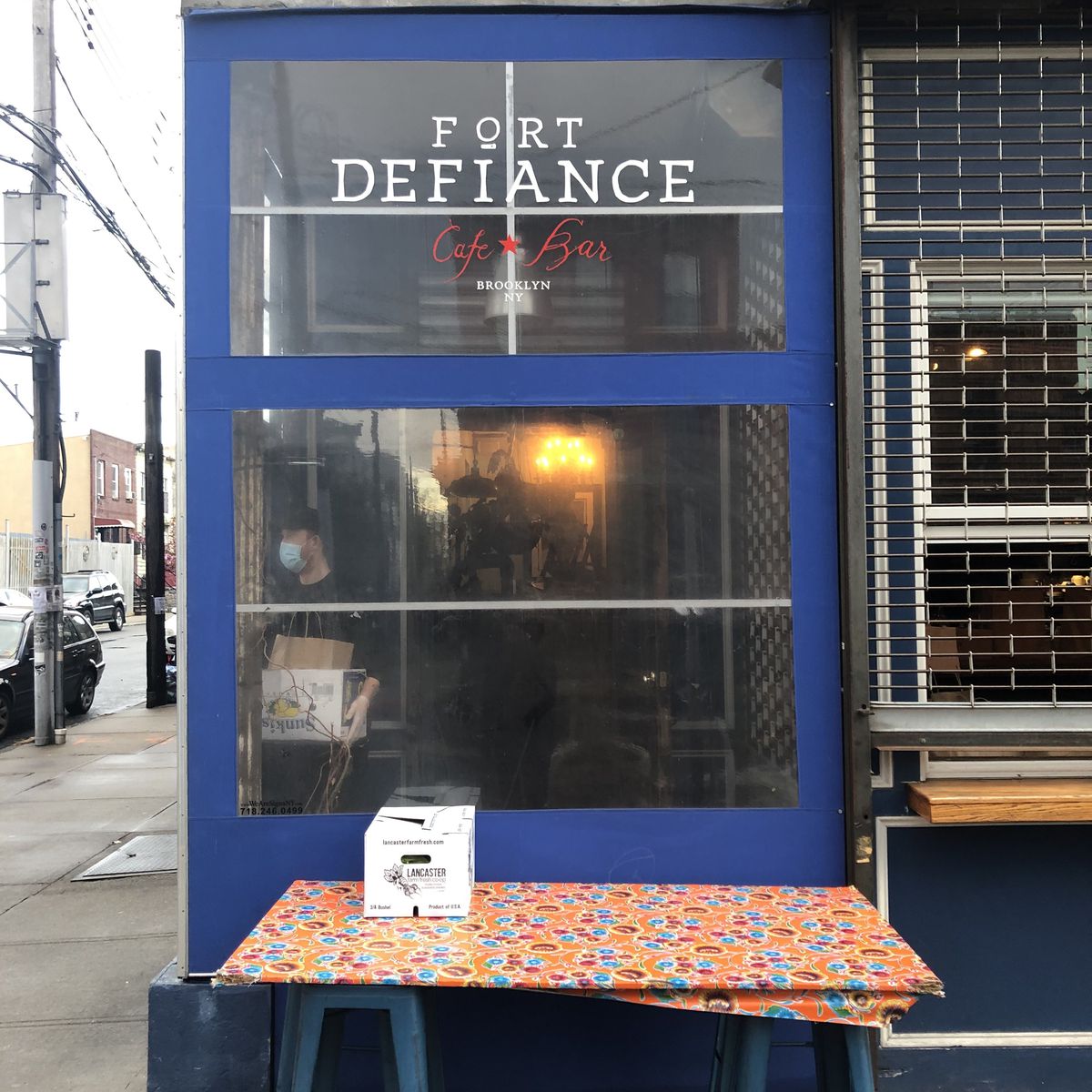 The exterior of a restaurant with a blue insulation box in the front and a table set outside of it