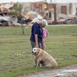 Kay Taylor stands with her dog Bailey in front of her house that was destroyed after the tornado that hit the area near 149th and Drexel on Monday, May 20, 2013 in Oklahoma City, Okla. 