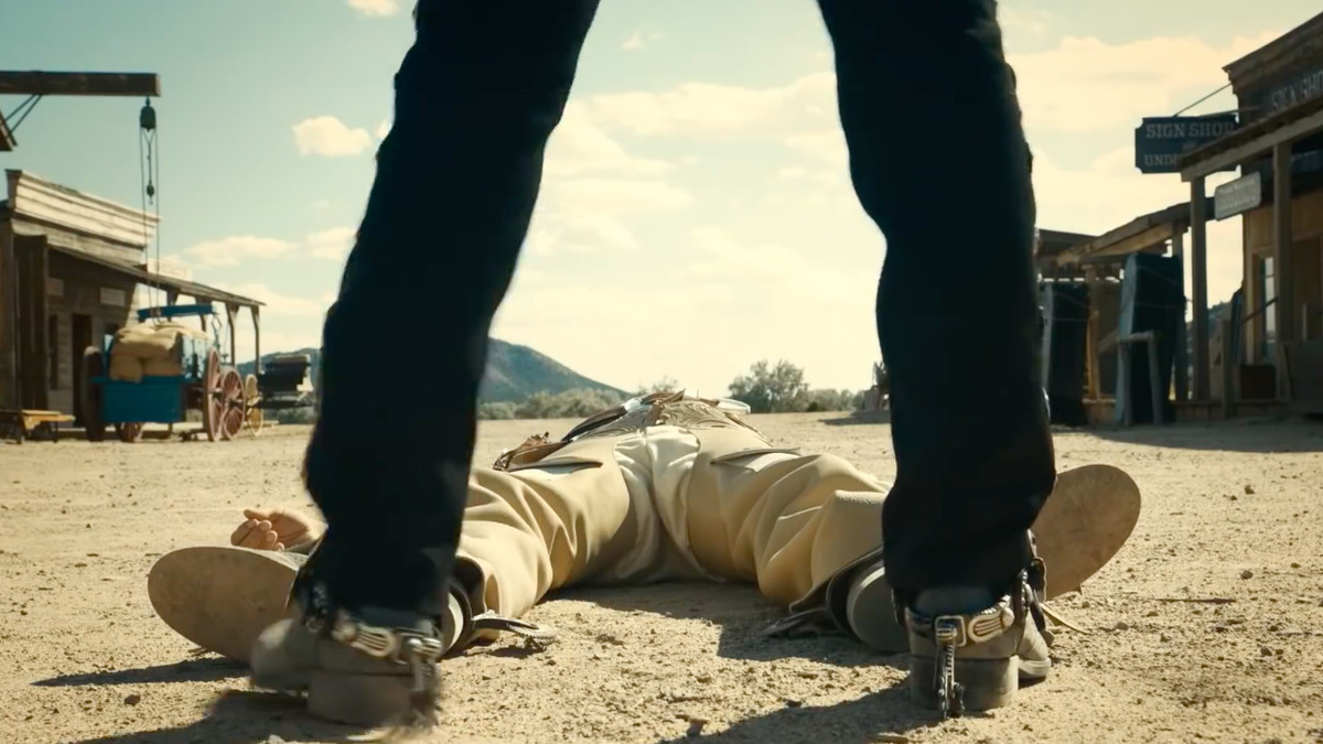 The Ballad of Buster Scruggs - man standing in front of a body lying on the ground