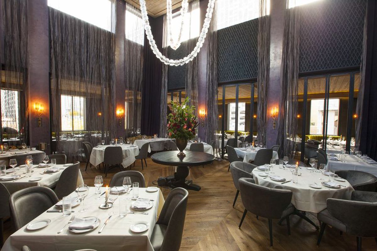 Maple &amp; Ash steakhouse with a big dining room with an elegant hanging chandelier.