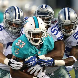 Aug 4, 2013; Canton, OH, USA;  Miami Dolphins running back Daniel Thomas (33) is tackled by Dallas Cowboys linebacker Caleb McSurdy (56), outside linebacker DeVonte Holloman (57) and defensive back Brandon Underwood (23) during the first quarter at Fawcet