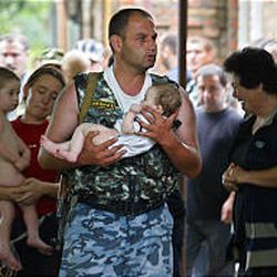 A special forces soldier and a woman carry children last year after the school siege in Beslan, in which 331 died.