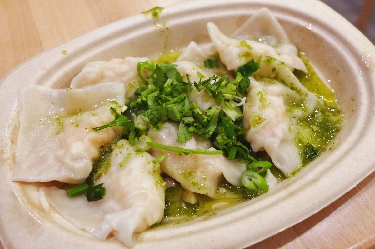 A plate of dumplings covered with green sauce.