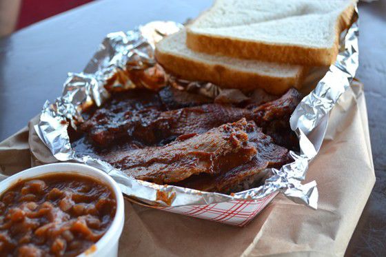 A paper boat filled with saucy ribs and white bread at Woody’s Bar-B-Q