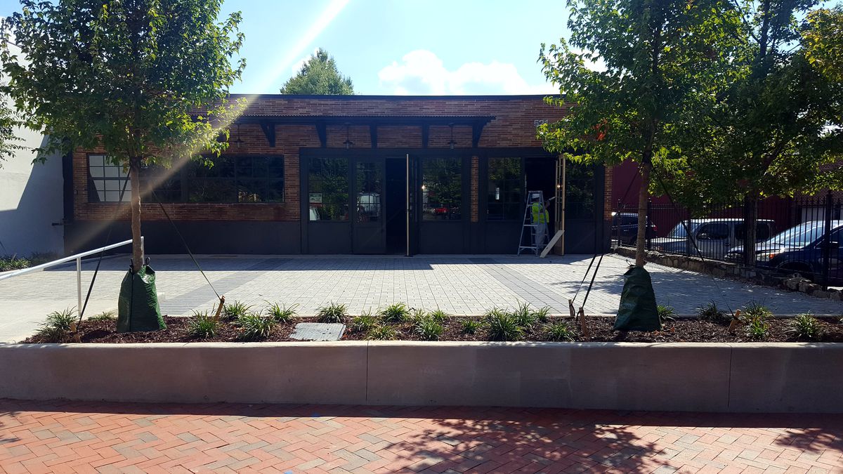 A picture of a red brick building with a grey brick front patio space.
