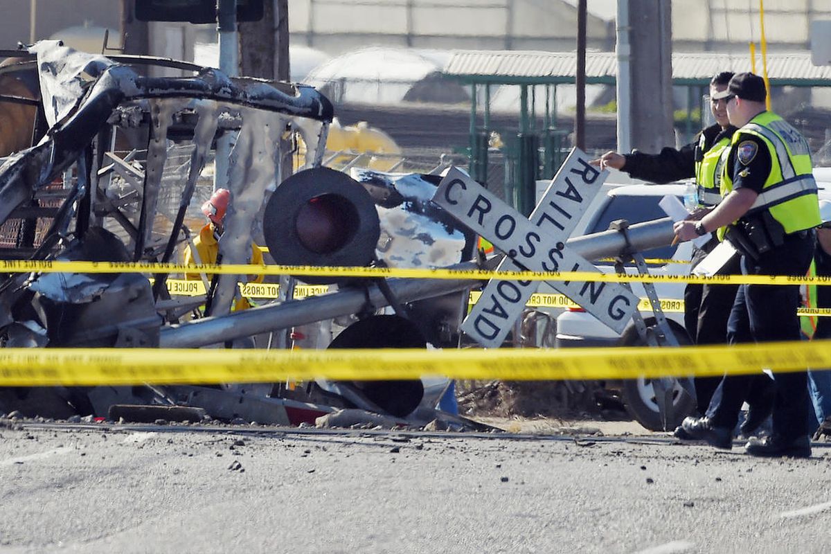 In this Tuesday, Feb. 24, 2015, photo police officers stand near a Metrolink train that hit a truck, left, and then derailed at a railroad crossing in Oxnard, Calif. 
