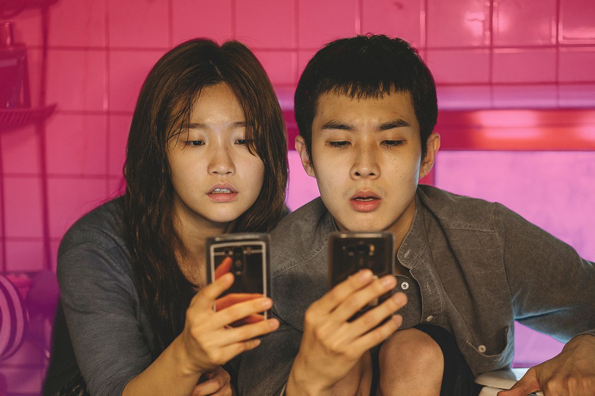 Ki-jung (Park So-dam) and Ki-woo (Choi Woo-shik) from the film ‘Parasite’ stare intently at their phones