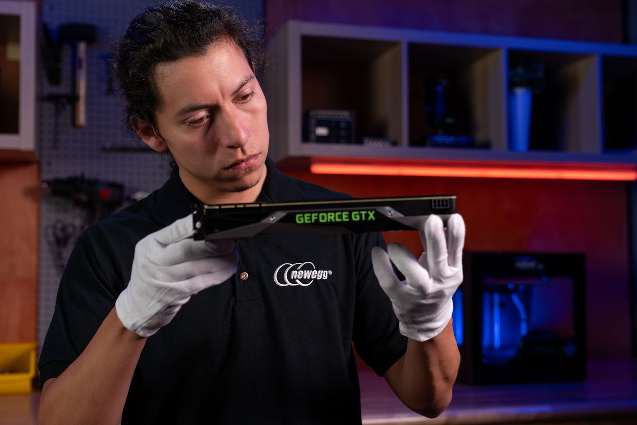 Image of a serious-looking man with black hair and white cotton gloves examining an Nvidia Geforce GTX graphics card. Hey, wait a minute, those aren’t even eligible for this program!