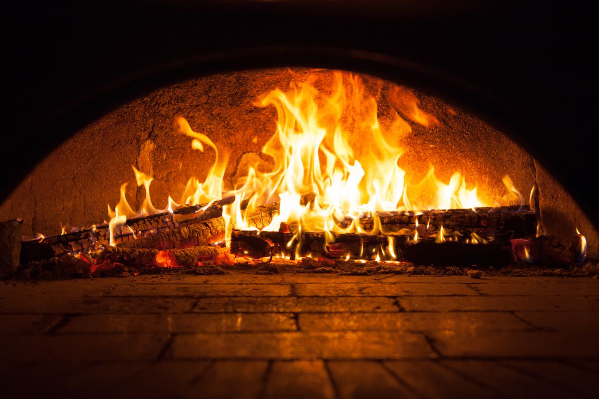 A wood-fired oven with blazing orange flames.