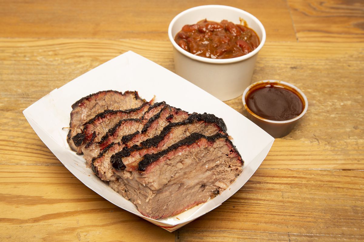 A paper container holds slices of smoked brisket.