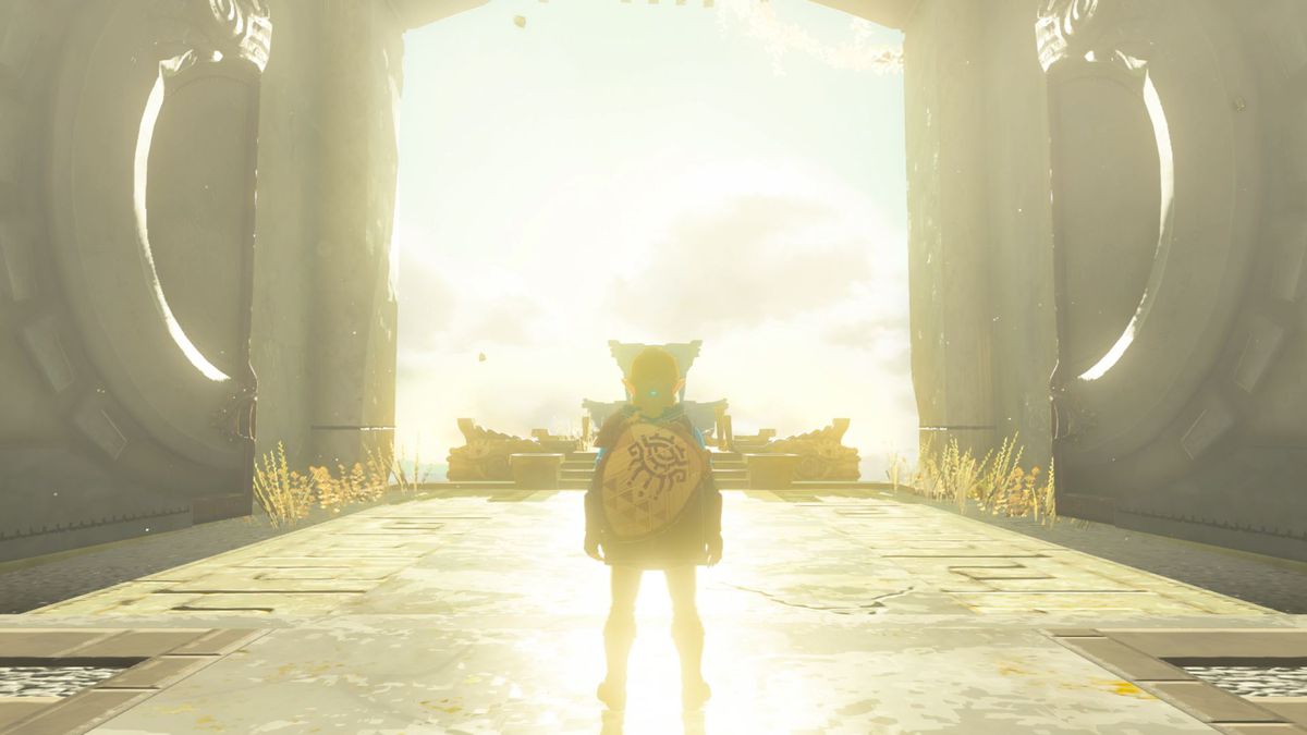 Link standing in a giant open doorway in The Legend of Zelda: Tears of the Kingdom. The light is glowing gold and the doors open up to the sky.