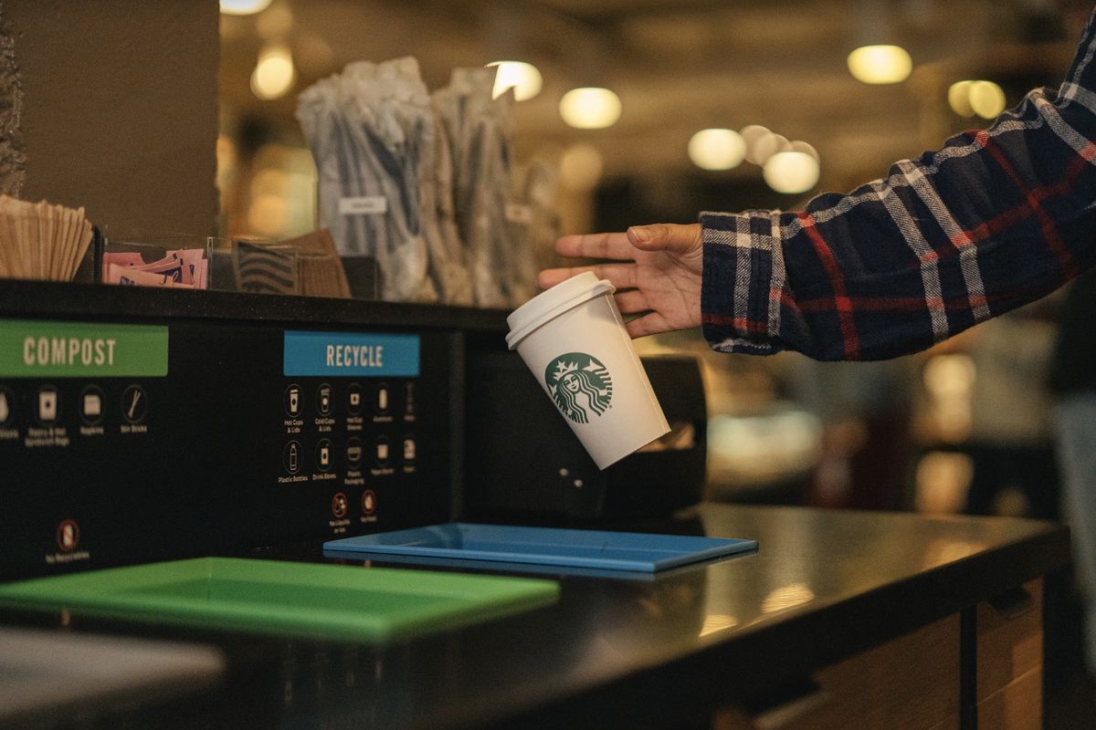 A customer discards a Starbucks cup in a recycling bin