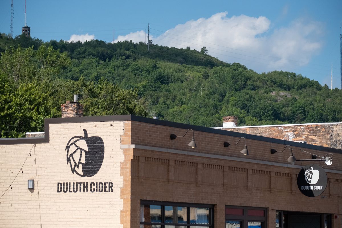 The top of the brick exterior of Duluth Cider with a view of Enger Tower and the hill in the background