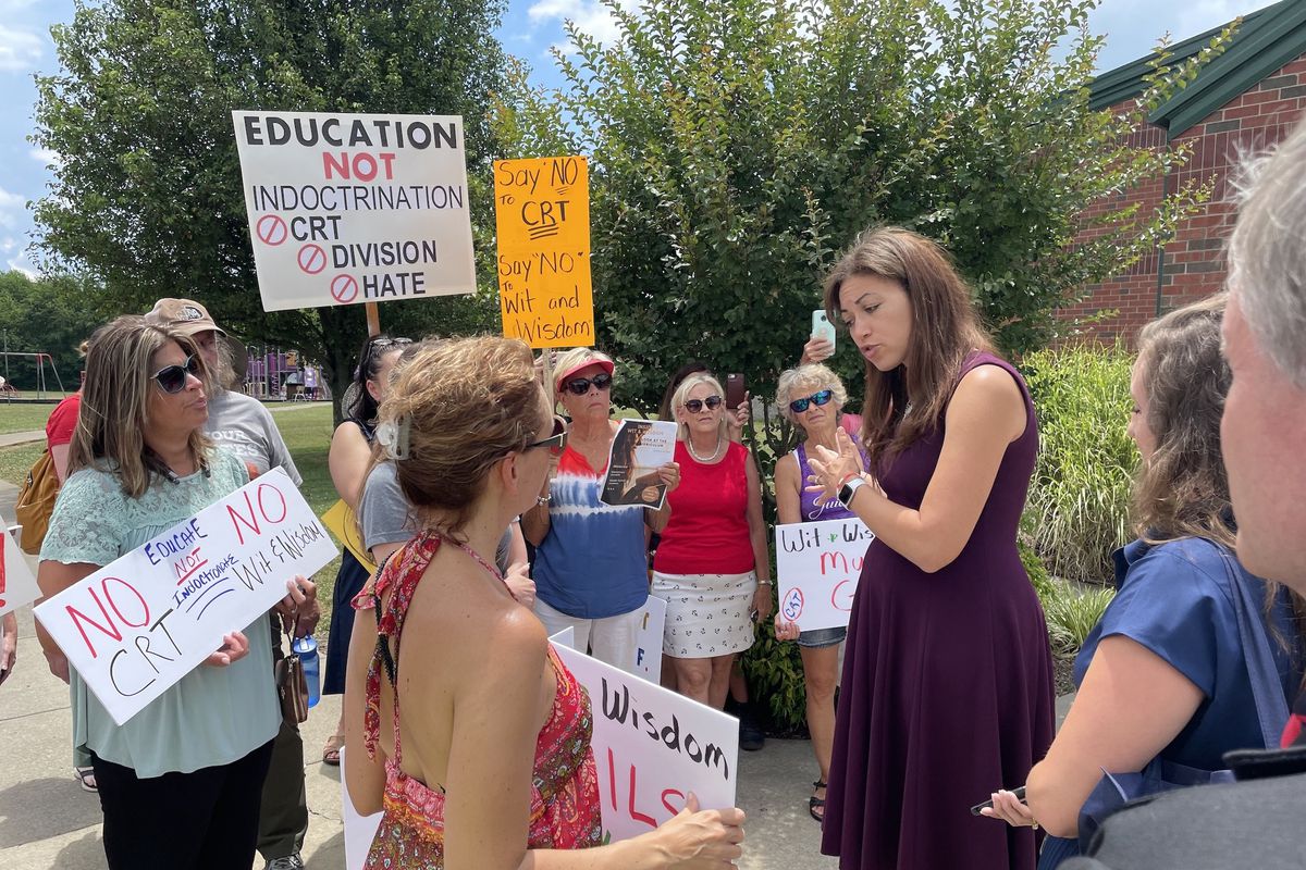 State Commissioner of Education Penny Schwinn talks to a small group of about a dozen protestors outside near a school.