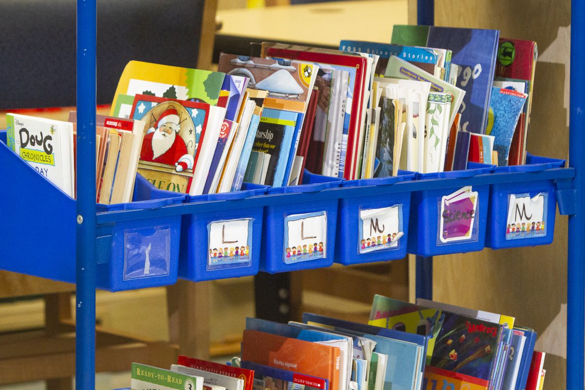 A blue cart of picture books organized alphabetically.