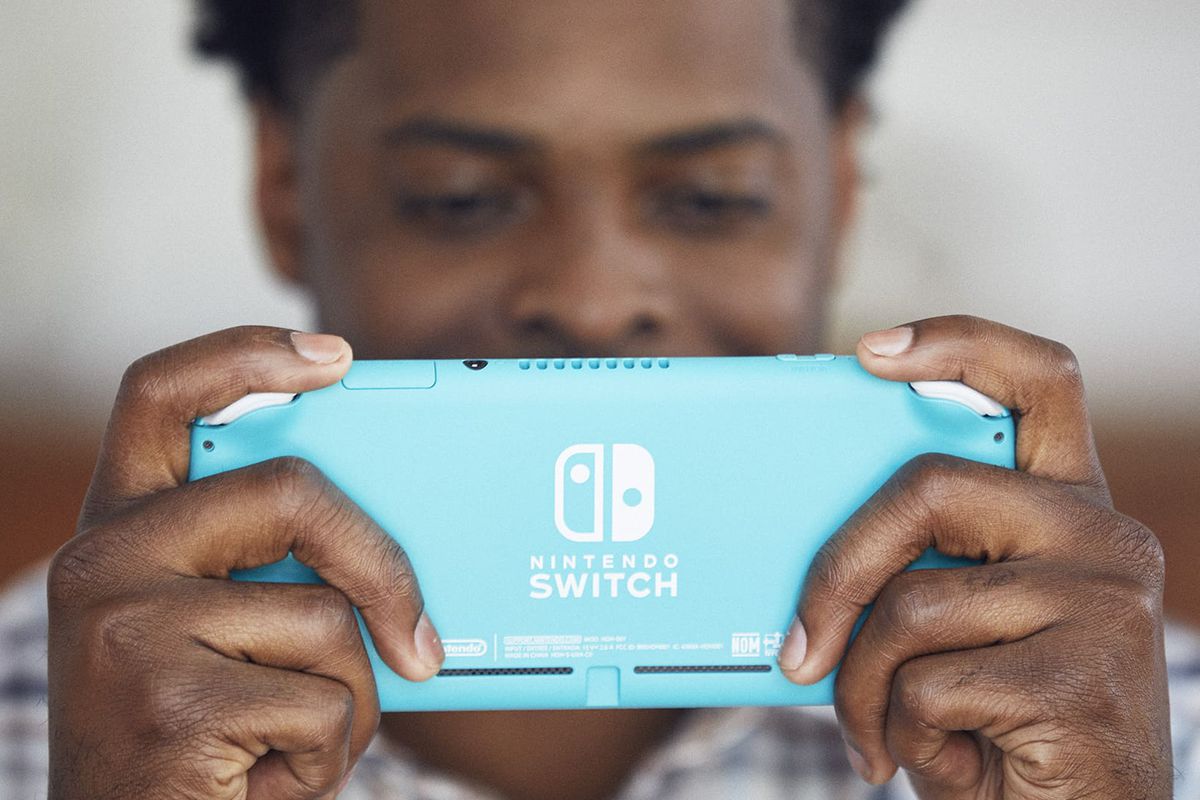 A Black man holding a turquoise Nintendo Switch Lite