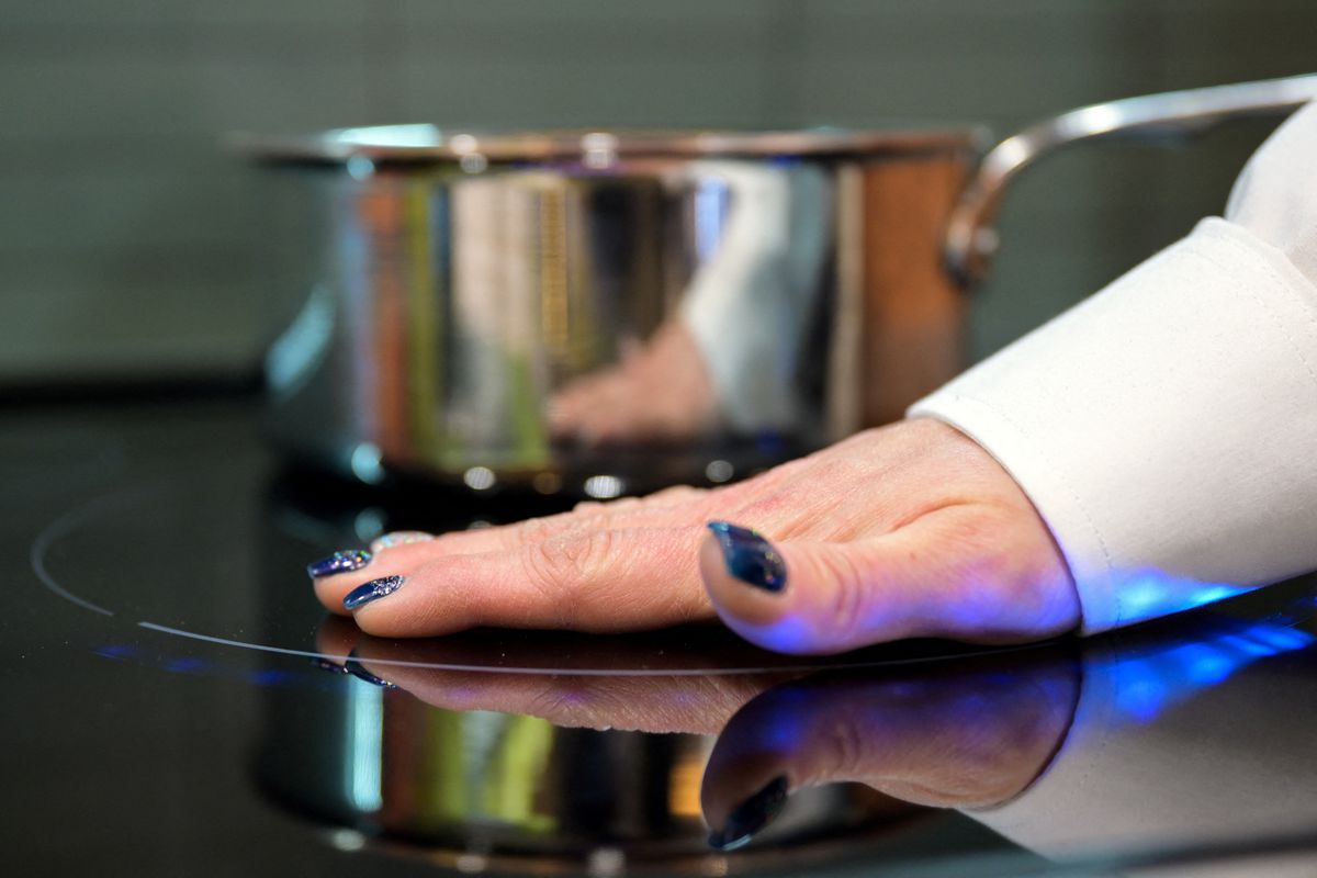A hand on an induction burner to demonstrate that it is not hot to the touch.