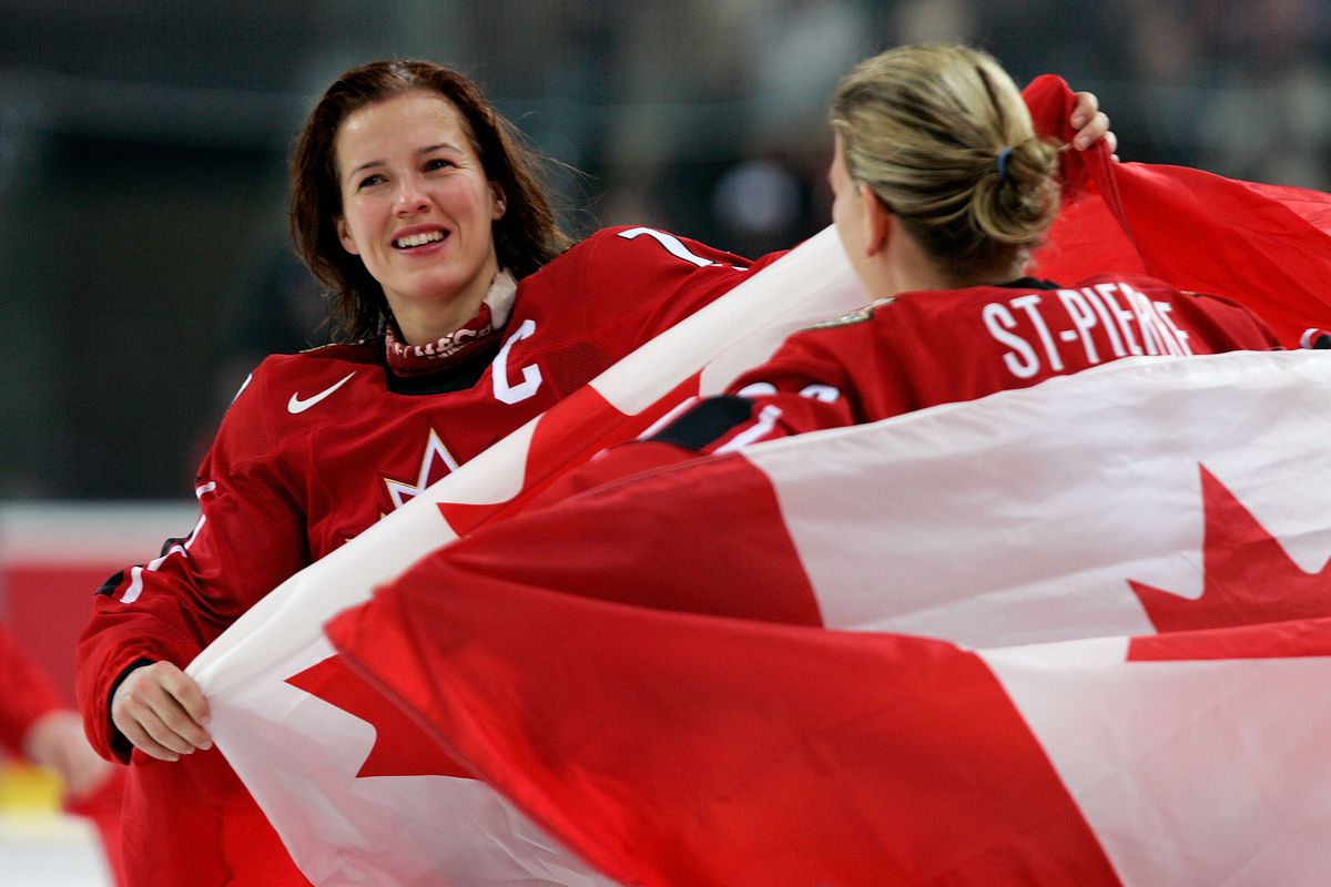 Cassie Campbell #77 and Kim St-Pierre #33 of Canada hold Canadian flags and celebrate their 4-1 victory over Sweden to win the gold medal in women’s ice hockey during Day 10 of the Turin 2006 Winter Olympic Games on February 20, 2006 at the Palasport Olim