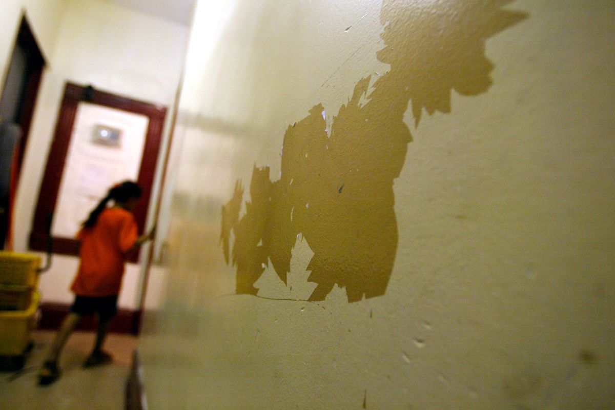 Children that have high levels of lead in their blood walk past a peeling lead paint wall July 25, 2003 in their apartment in Brooklyn. (Photo by Spencer Platt/Getty Images)