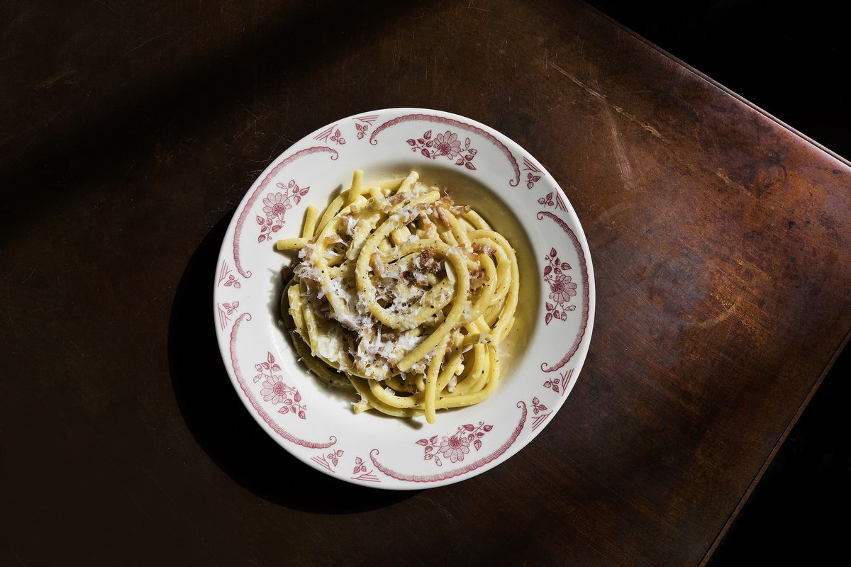 An overhead shot of thick Italian noodles with cheese on a wooden table.