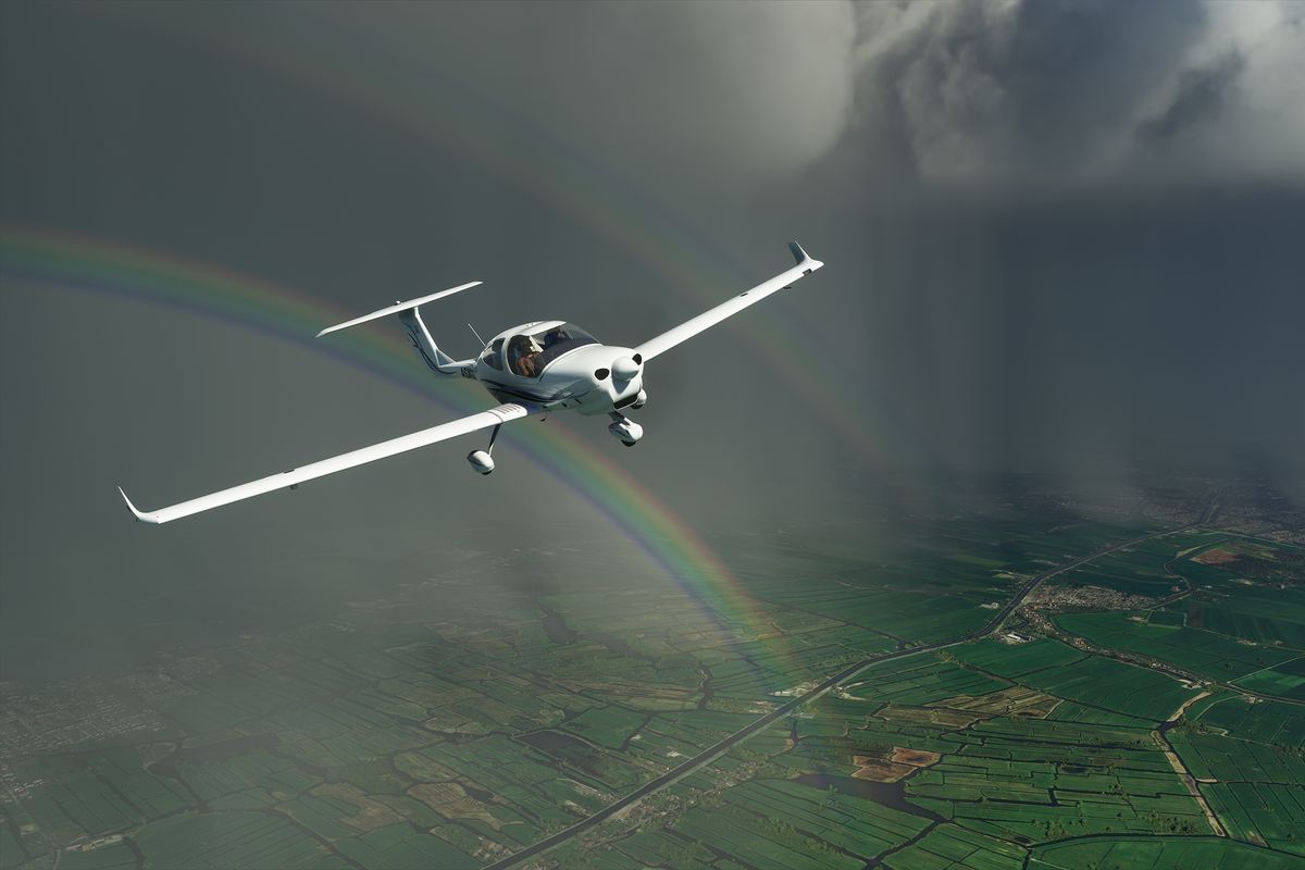 A single-engine plane flys before a rainstorm with a rainbow in the background. The city is Amsterdam.