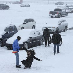 A woman is helped up after making a snow angel in a parking lot outside the Wells Fargo Center during a winter storm after an NHL hockey game between the Philadelphia Flyers and the Nashville Predators, Saturday, Feb. 21, 2015, in Philadelphia. 