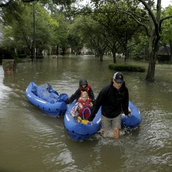 People evacuate a neighborhood inundated by floodwaters from Tropical Storm Harvey on Monday, Aug. 28, 2017, in Houston, Texas.