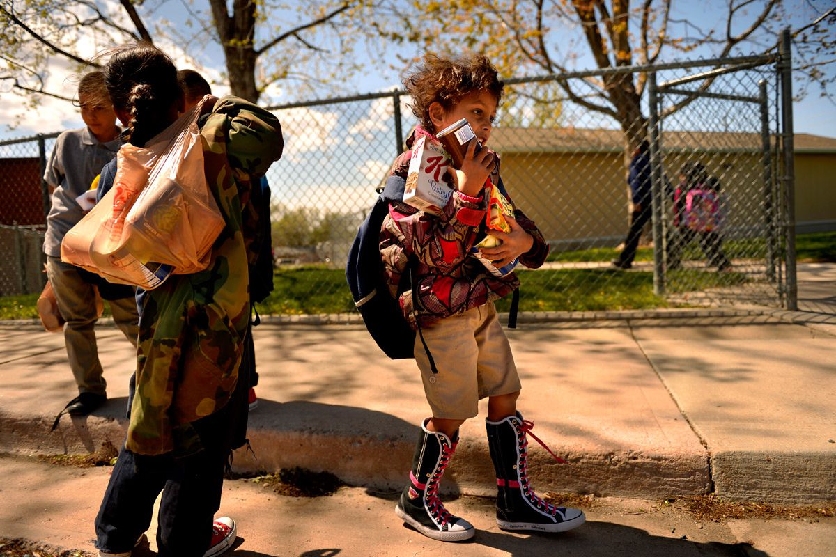 Homeless children in Aurora walk with bags of donated food after school.