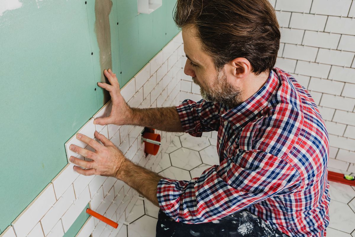 A man laying tile in a bathroom