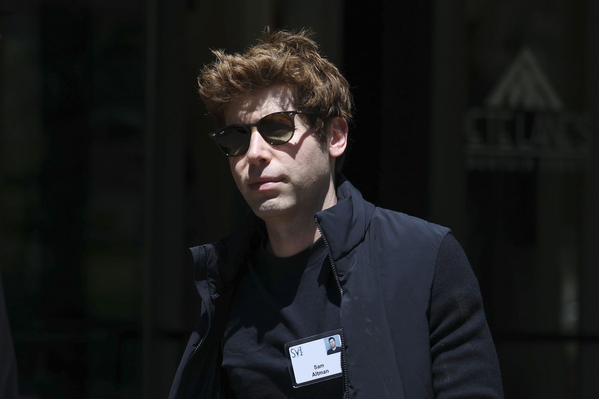 A close-up of OpenAI CEO Sam Altman wearing a black shirt and black sunglasses.