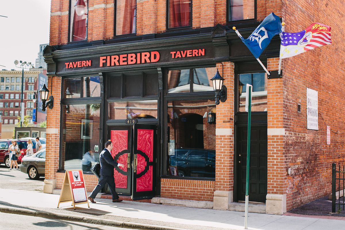 A man walks through the Firebird Tavern’s red and black on a winter day with snow still patchy on the ground.